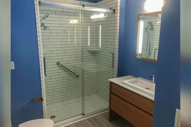 Beach house bathroom remodel with a subway-look acrylic shower, sliding glass door, wood vanity and blue walls