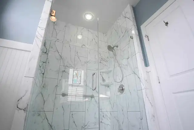 Walk-in shower replacement with marble-look walls, glass enclosure and white wainscoting